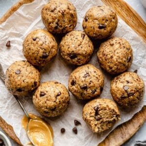 No-bake peanut butter protein bites with dark chocolate chips on a wooden plate.